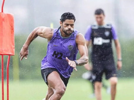 Jogador Hulk em atividade de corrida e explosão muscular durante treinamento físico intenso de futebol profissional sob chuva, ilustrando a importância da preparação física e força no esporte moderno.