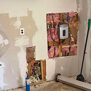 Pared con reparaciones, tuberías expuestas y calentador de agua