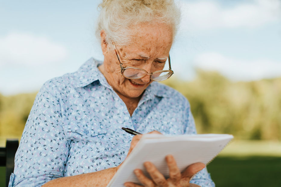 Mulher idosa concentrada escrevendo em um caderno