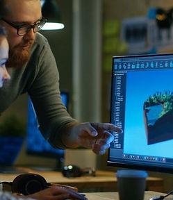 Two people using 3d modelling software on a computer.