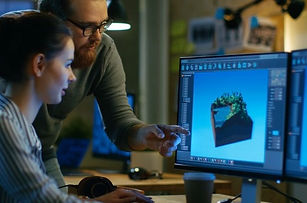 Two people using 3d modelling software on a computer.