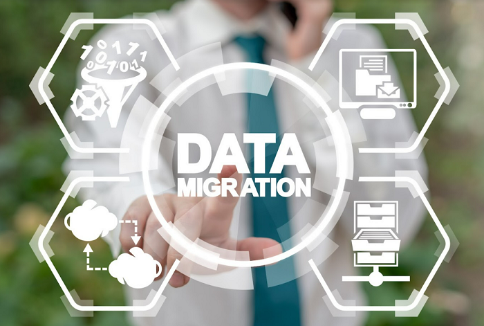 Person in tie interacts with virtual screen labeled "DATA MIGRATION," surrounded by tech icons, on a blurred green background.