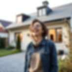 Une femme ravie devant sa maison rénovée.jpg