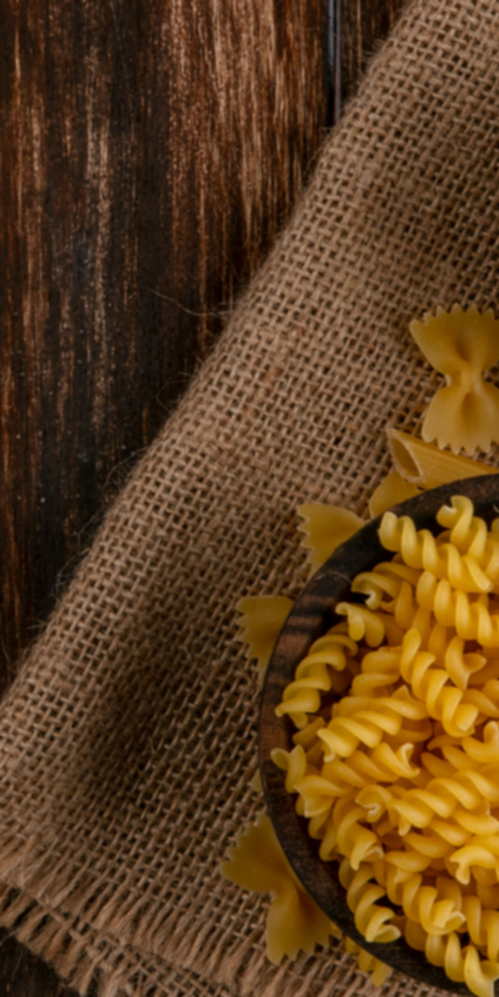 top-view-of-raw-spaghetti-with-raw-pasta-on-a-beige-napkin-on-a-wooden-surface.jpg