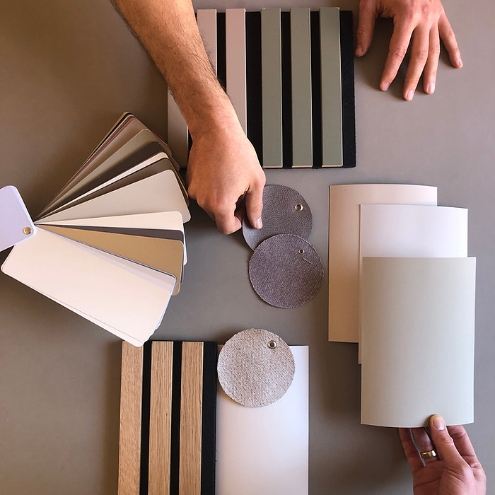 Hände ordnen Materialien, Farben und Oberflächen zu einem stimmigen Raumkonzept im gemeinsamen Gestaltungsprozess