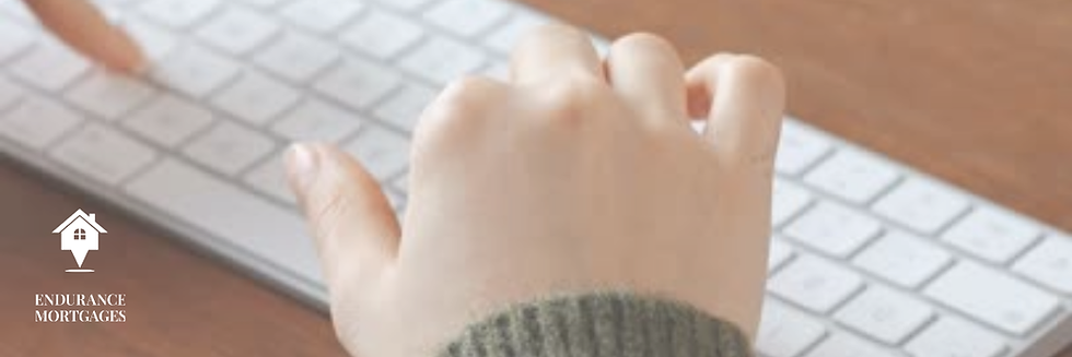 Hand typing on a white keyboard beside the Endurance Mortgages logo on a wooden desk.