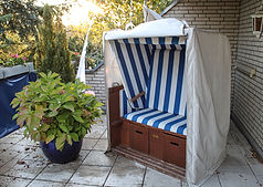 OFFEN_Strandkorb abgedeckt auf Terrasse im Abendhimmel