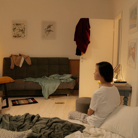 Woman slouching while sitting in a cluttered living space showing how environment impacts mental health, stress, and energy levels