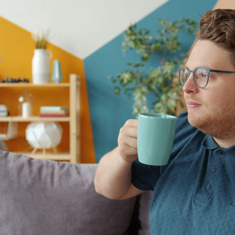 Man doing a simple daily habit like drinking tea in a calm, relaxing home environment, representing sustainable self-care and mental wellness