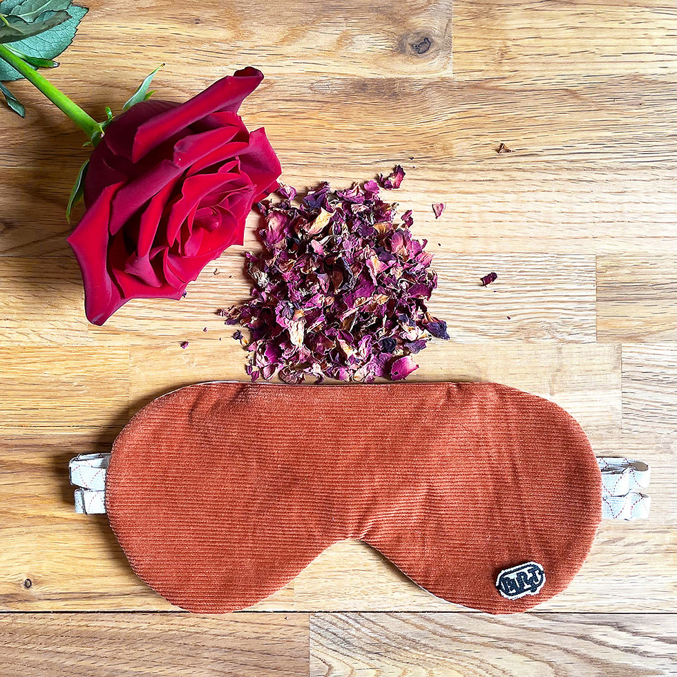 Miniaturbild: handgemachte naturfreundliche schlafmaske in terracotta orange von burst vorderansicht mit rosenblütenblättern auf holz