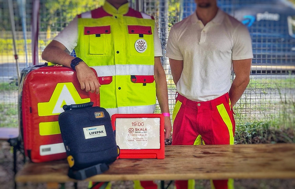 Zwei Sanitäter von SKALA Paramedics stehen an einem Tisch, auf welchem sich Einsatzmatetial befindet.