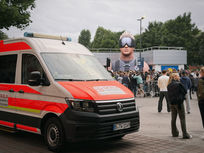 Zwei rot-weiße Volkswagen Einsatzfahrzeuge von Skala Paramedics Sanitätsdienst parken nebeneinander auf einem gepflasterten Gelände vor einer grauen Gebäudewand unter bewölktem Himmel; das vordere Fahrzeug zeigt das Berliner Kennzeichen B TW 1149.