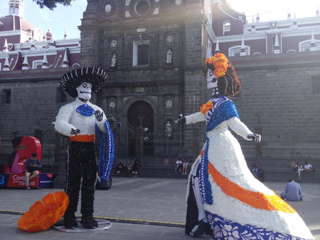 Familias poblanas y turistas disfrutan de los adornos del día de muertos en el Zócalo de la ciudad.