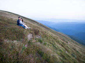 A couple sitting on a hillside.