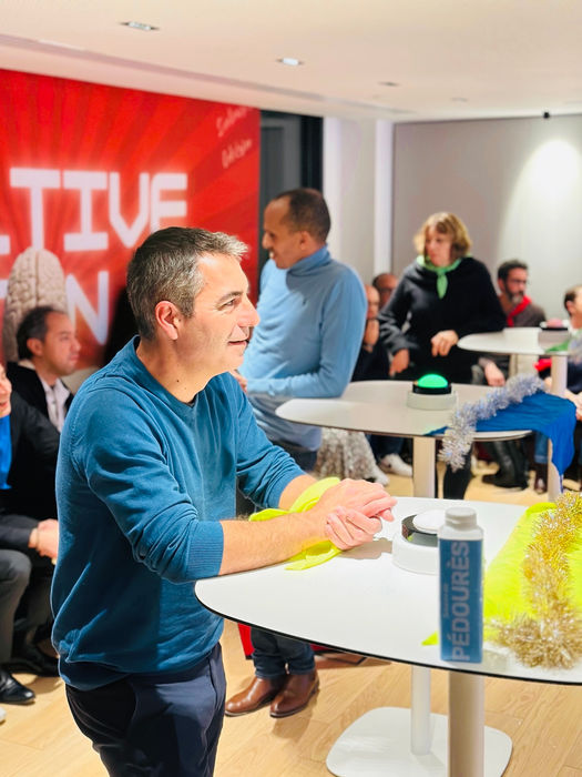 Personnes devant pupitres et buzzer du quiz des champions