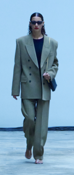 A model walking down the runway in an oversized blazer with shoulder pads and matching trousers, from the Khaite Fall 22 collection runway presentation