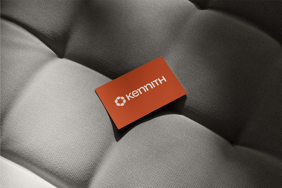Kennith Infraventures business card mockup in orange with modern geometric white logo, showcasing professional brand identity for architecture and interiors.