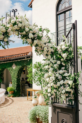 white garden style flowers on the entrance gate to a Il Mercato wedding by Leaf + Petal NOLA 