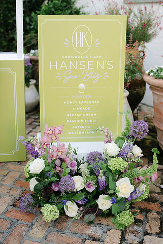 Custom snowball station sign accented with colorful garden florals at an Il Mercato wedding.