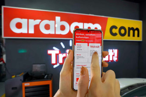 Araba.com uygulamasında parmağı ile dokunan bir el, araba alırken, satarken, kullanırken.