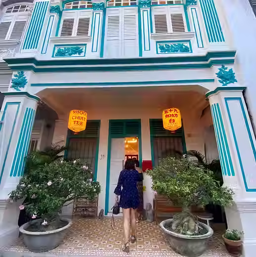Guest entering the @59JCT shophouse with yellow lanterns and courtyard plants, Joo Chiat