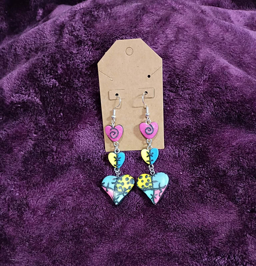 Triple-heart patchwork dangle earrings with pink, teal, and yellow "stitched" designs on a purple textured background.