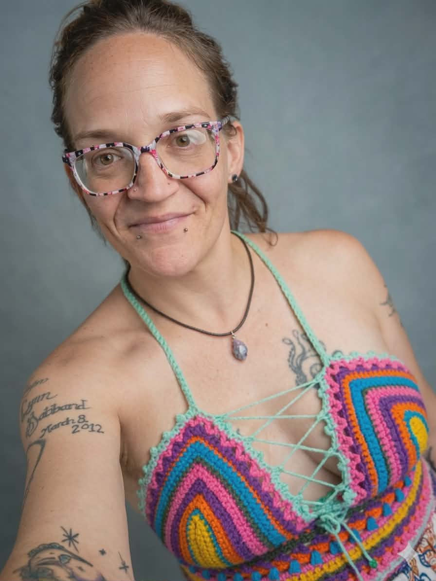 Artisan-Crafted lace-up crochet crop top with a vibrant rainbow chevron pattern and a teal lace-up front. viewed from front