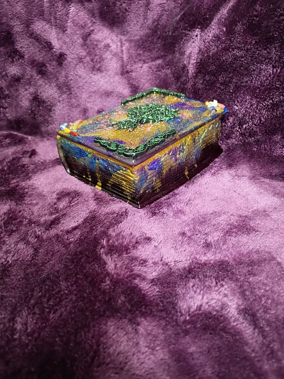 Angled View of a closed, book-shaped trinket box with a green Tree of Life on a plush purple background