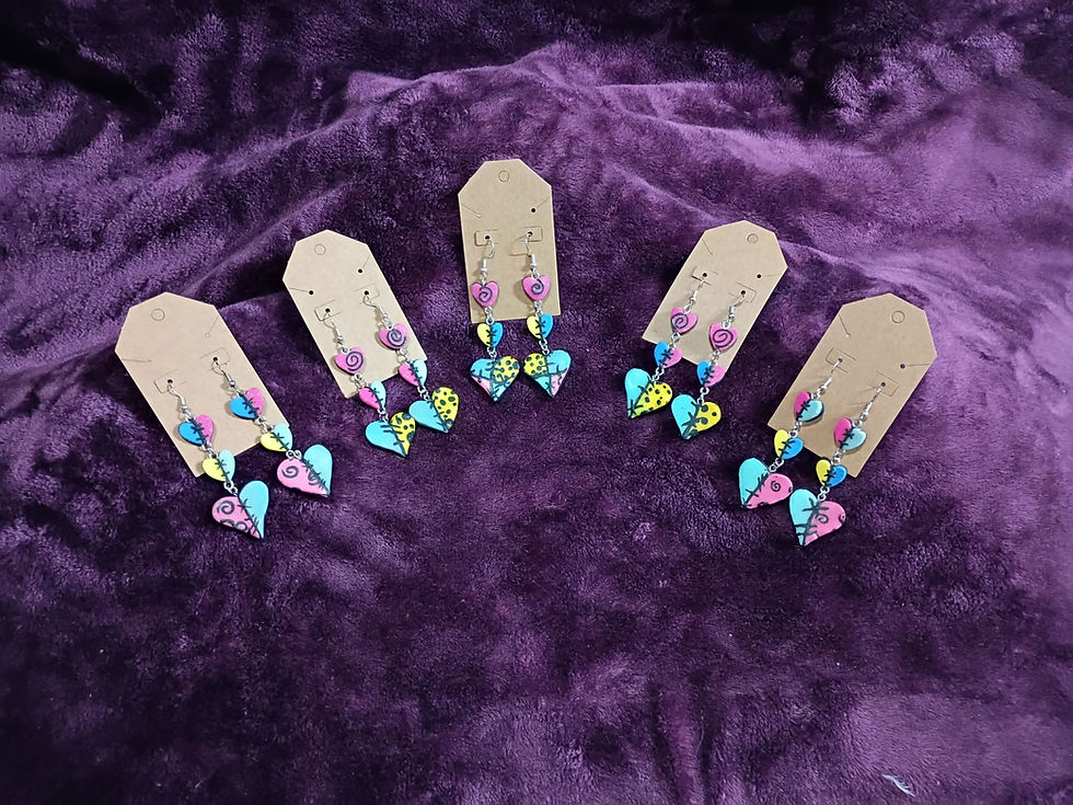 Five pairs of patchwork heart earrings in vibrant colors with hand-sculpted stitches on a purple velvet background