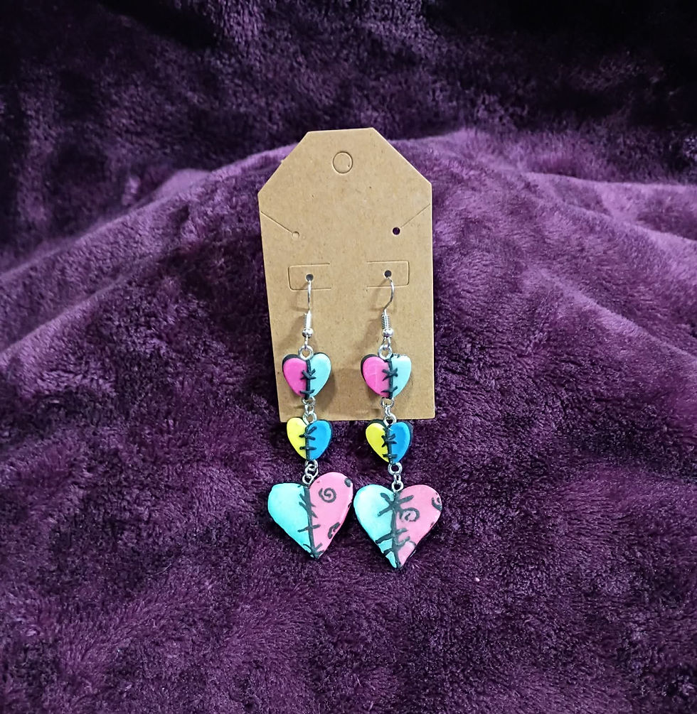 Thumbnail: Triple-heart patchwork dangle earrings with vibrant colors and hand-sculpted stitches against a purple velvet background.