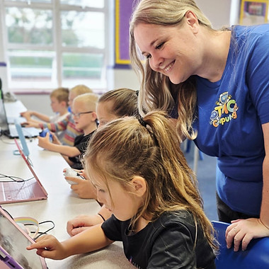 TMC Computing Club Leader smiling at a child's coding efforts during Minecraft Club