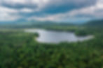 Aerial view of a forested Adirondack lake surrounded by mountains in Northern New York