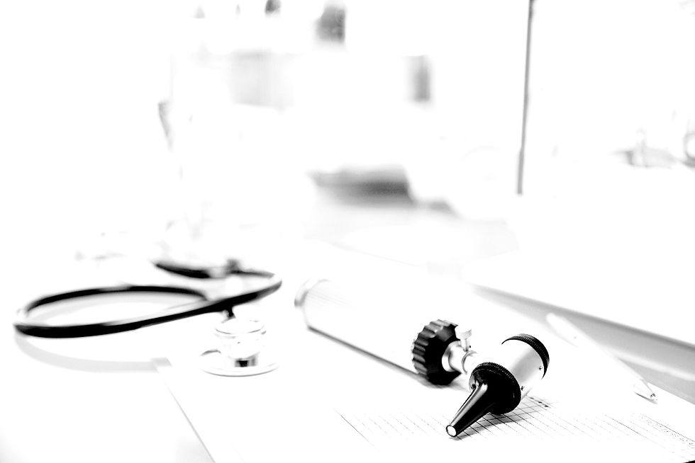 Medical tools including an otoscope and stethoscope rest on a desk, suggesting a clinical or diagnostic setting.