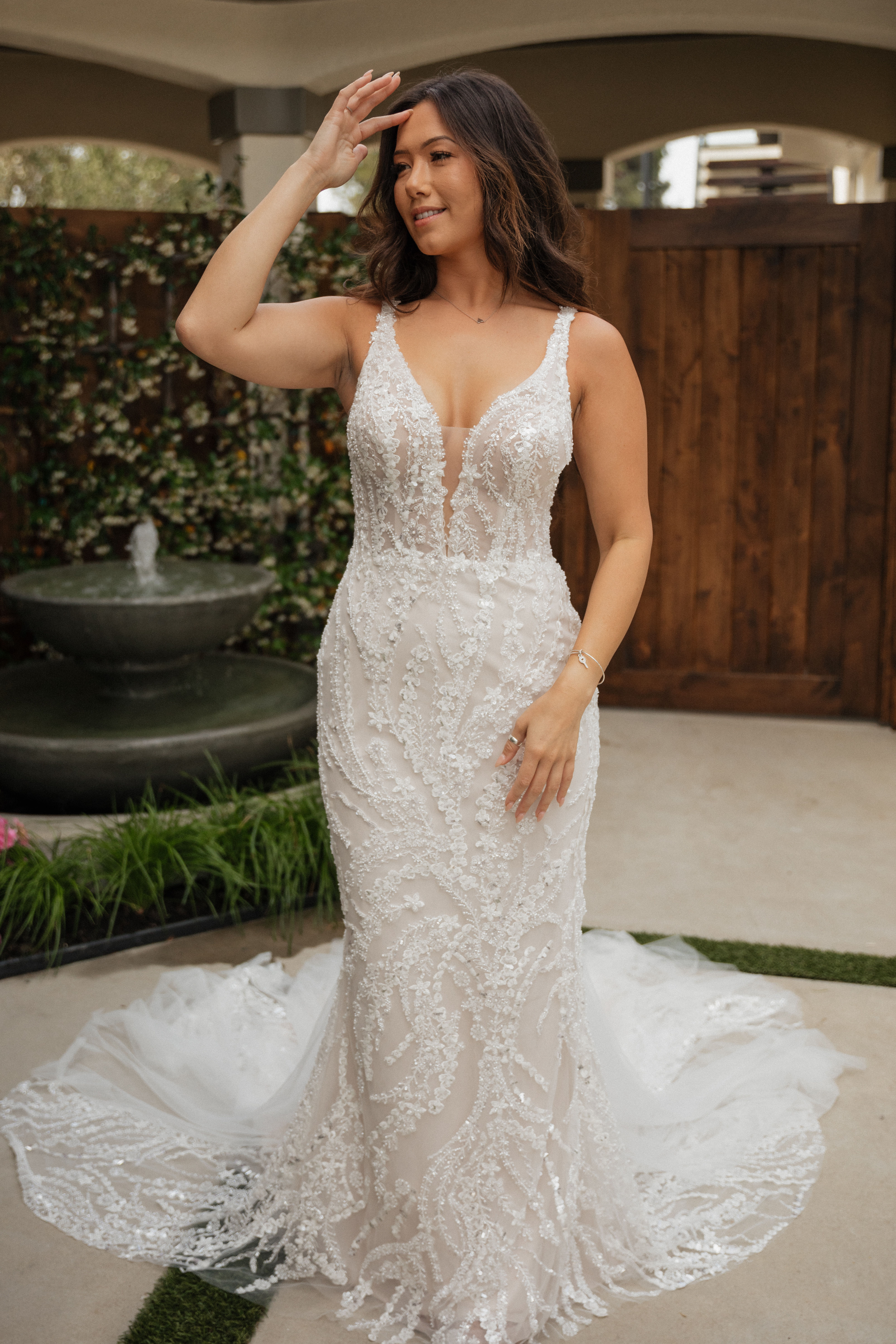 Ariana | S25509
Gown Info
This gown is a masterpiece of elegance and grace, blending floral fabric with layers of tulle, all atop a comfortable knit lining with a bodysuit inside. Adorned with delicate beaded fabric lace, it exudes timeless sophistication and intricate craftsmanship. The Deep V-neckline enhances the neckline with a touch of allure and modernity, while the mermaid silhouette flatters the figure with its graceful contours. 

Material
Lace/Tulle

 

Color & Size
Shown in Ivory/Champagne

Also available in Ivory/Ivory

Available Sizes: 2 - 28 / 14W - 32W Size Chart