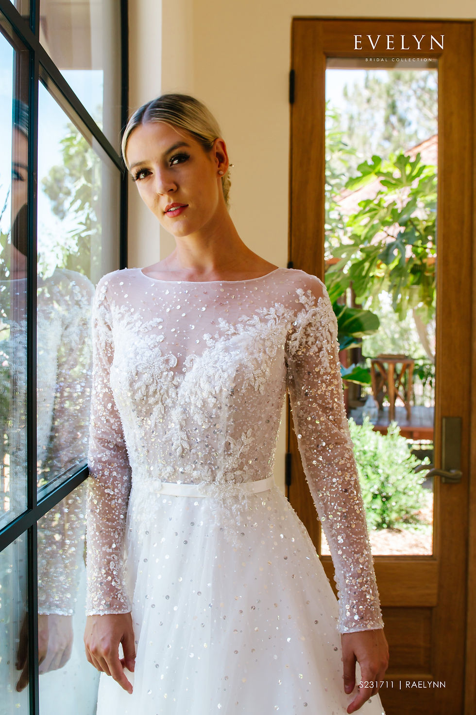 Thumbnail: Raelynn | S231711
Gown Info
Intricate sparkle throughout this lace and tulle long sleeve ball gown makes Raelynn the perfect dress for every bride wanting to make a statement. Raelynn features an illusion bateau sparkle tulle neckline, illusion off the shoulder lace design with sheer sparkle tulle sleeves and a classic satin belt. The covered buttons on the back neckline and sparkle tulle on the skirt add the perfect touch to this chapel length train beauty.

Material
Lace/Tulle

Color & Size
Ivory/Champagne

Ivory/Ivory

Sizes available - 2-28 / 14W-32W