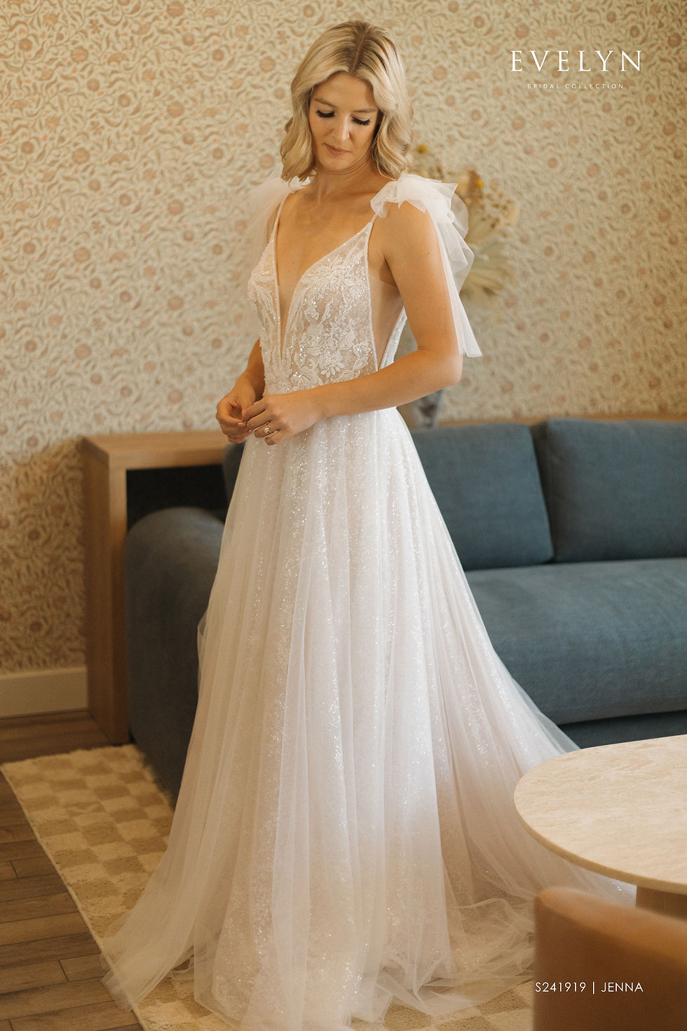 Thumbnail: Radiate elegance in this stunning wedding dress. The deep V-neckline complements the delicate tulle skirt, creating a whimsical look. Shimmering beadwork adorns the shoulder straps, featuring delicate tulle bows for a touch of enchantment. Sheer lace panels add allure to the diagonal sides of the upper body. Crafted with sparkling sequin tulle fabric, the upper body and second layer of the skirt exude a luminous glow. Lace appliques and beads embellish the upper body, while a convenient zipper and button closure adorn the back. Embrace the perfect blend of elegance and allure on your special day with this extraordinary gown.
