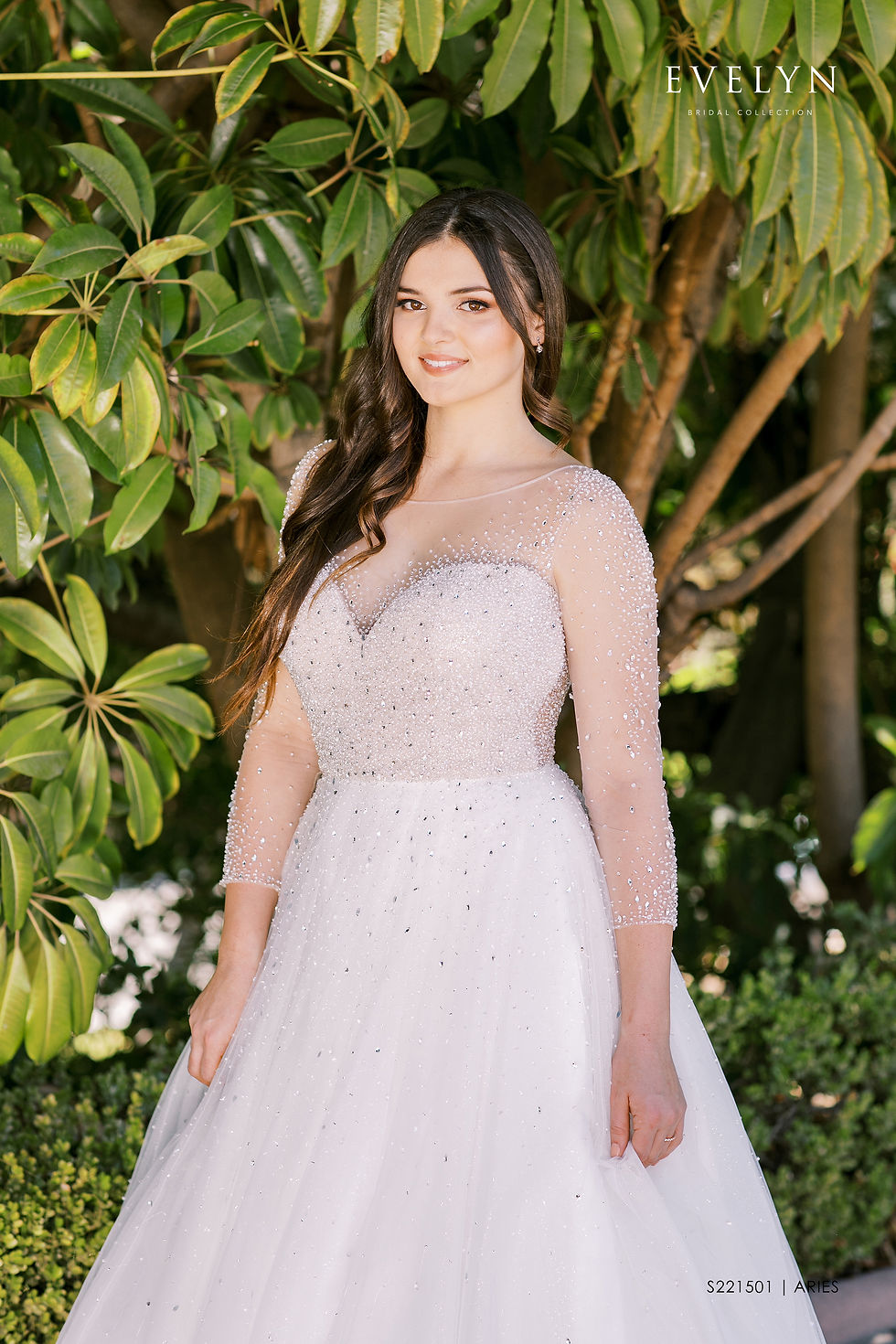 Thumbnail: ARIES | S221501
Gown Info
Long sleeve tulle ball gown with a glamorous, old Hollywood vibe. The illusion bodice is adorned with sparkling crystals that embellish the neckline and sleeves. The skirt features a chapel length train with cascading crystals at the waist.

Material
Lace

Tulle 

Crystal

 

Color & Size
Ivory/Nude (Shown)

Sizes available in 2-28  / 14W-32W