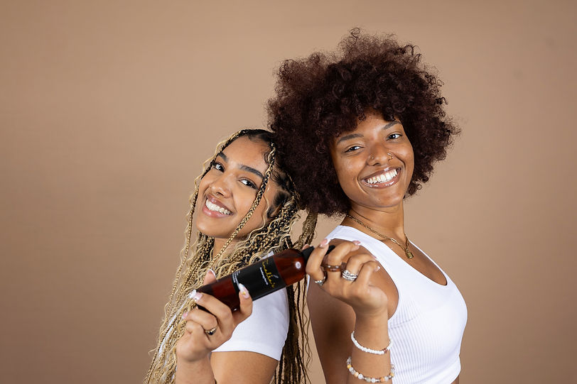 Image of two female models standing back to back holding a bottle of the product.