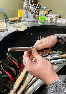 Jeweller taking a ring size at his work bench.