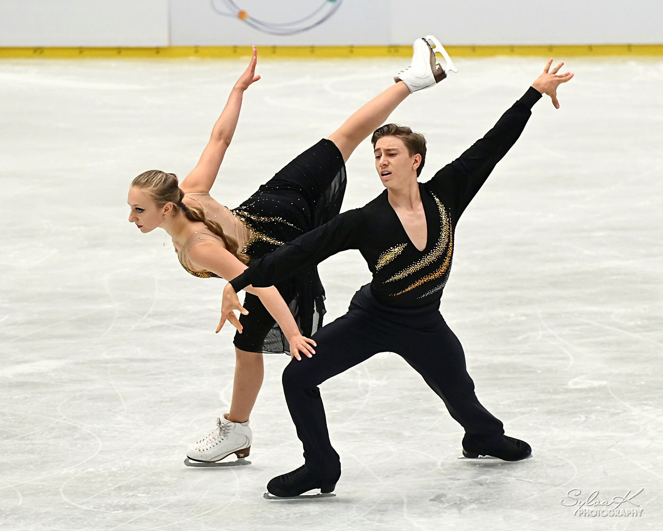 Český taneční pár, Juniorští mistři světa Kateřina a Daniel Mrázkovi při volném tanci na hudbu z filmu Muž se železnou maskou. Černé krasobruslařské kostýmy, sportovní fotografie Sylva Křenková.