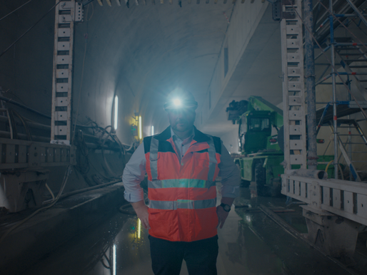 „Bauingenieur mit Stirnlampe und Warnweste im Tunnel, umgeben von Maschinen und Schalung – Symbol für modernen Tunnelbau, Technik und Infrastrukturprojekte unter Tage.