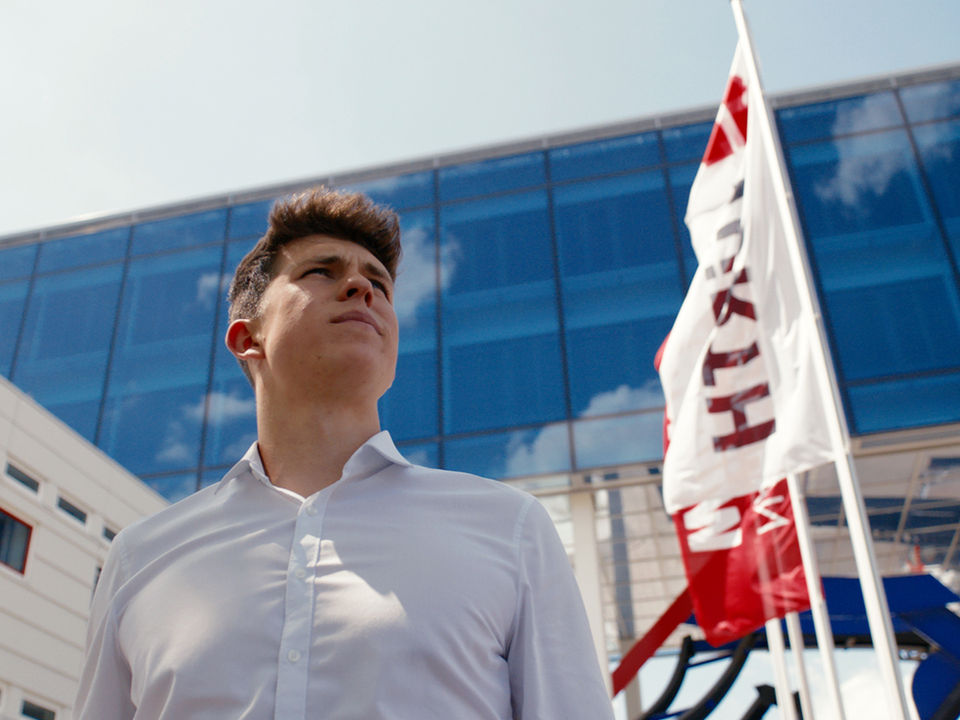 Student des dualen Studiums Betriebswirtschaft vor dem Würth Firmengebäude. Aufnahme aus einem Recruitingfilm der Adolf Würth GmbH & Co. KG.