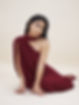 Woman in a one-shoulder burgundy dress sitting down
