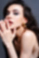 Woman with wavy dark hair wearing gold hoop earrings