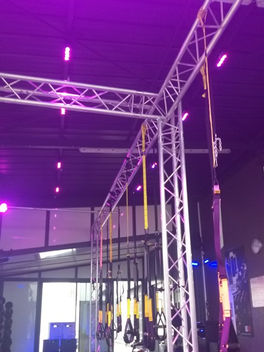 Structure métallique avec des lumières violettes et des équipements sportifs dans une salle. STORM SONO