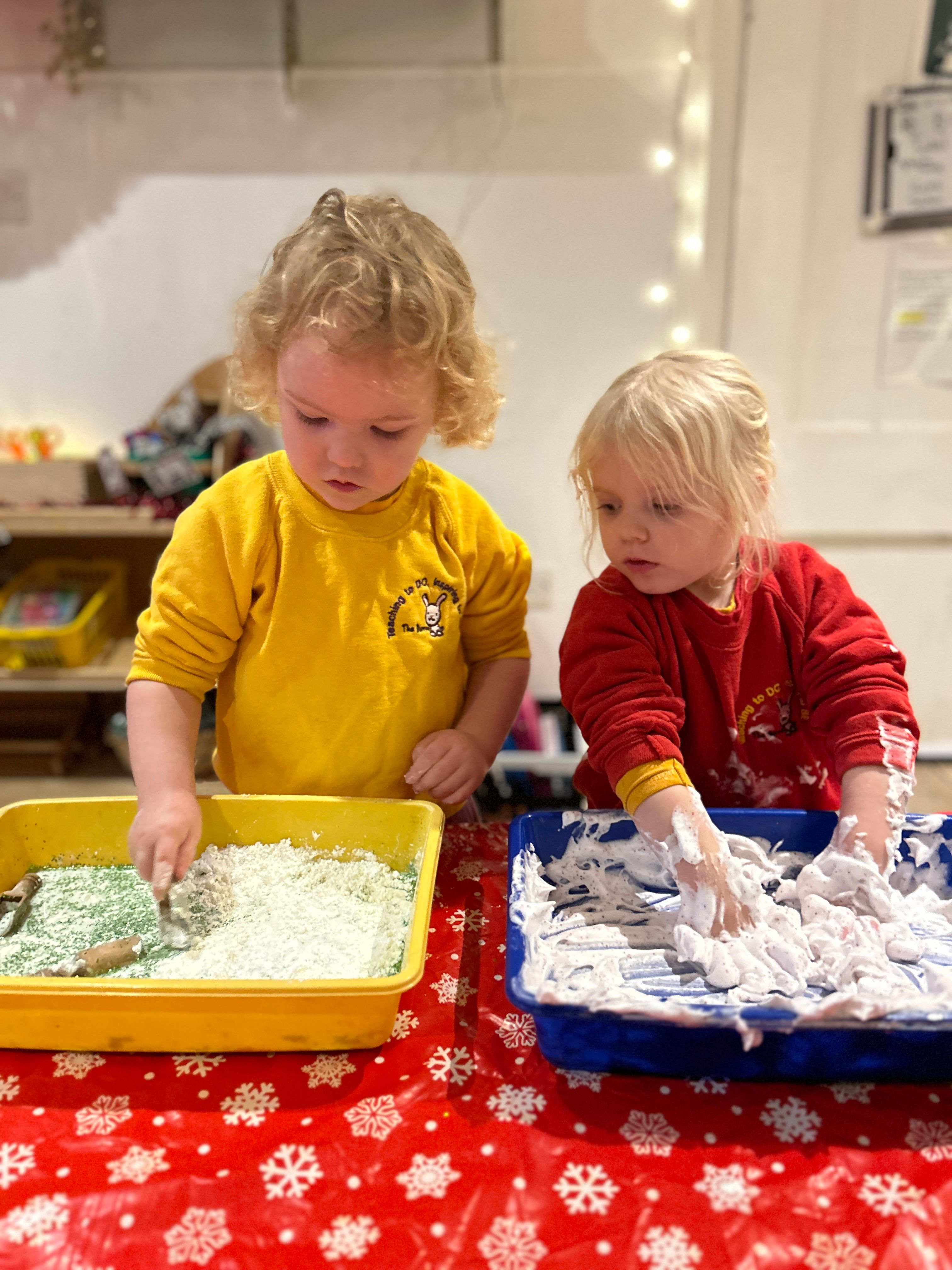 Two children playing in a water pit with shaving foam