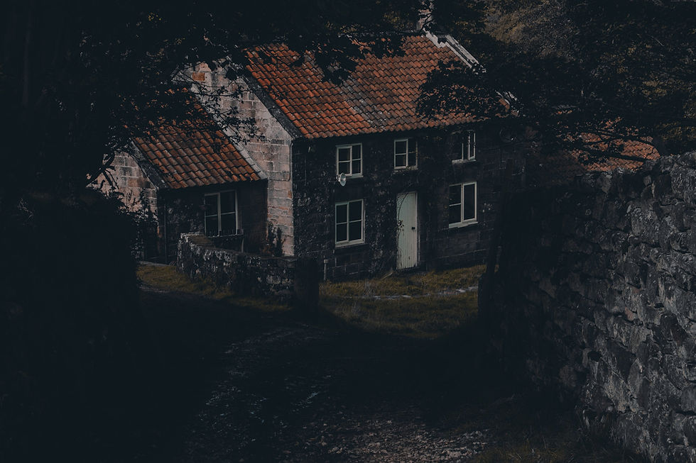 "A dark, moody photograph of an old Victorian-style brick jail under a full moon, with arched windows, a central tower, and leafless trees surrounding the haunted structure."