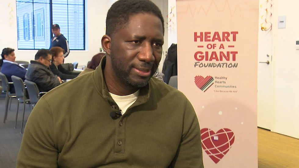 Bouba Dieme in front of the Heart of a Giant Foundation banner (WBZ Change Makers)