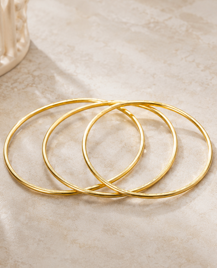 Thumbnail: 18K Gold Plated Classic Bangle Set laying flat on stone