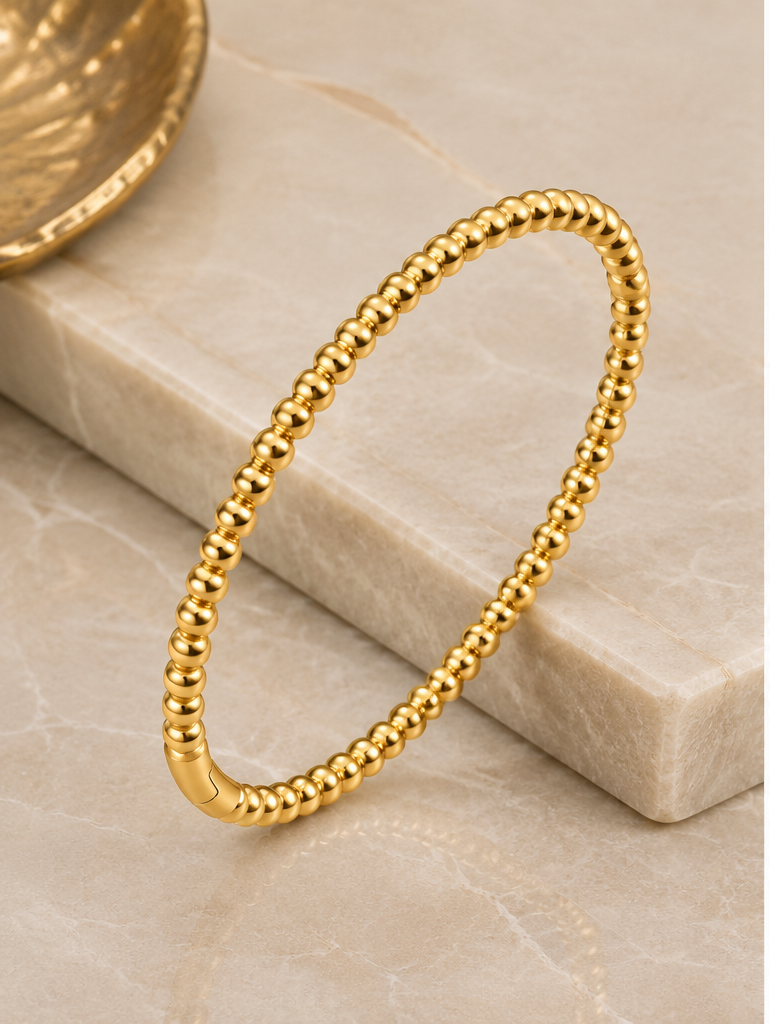 Thumbnail: 18K Gold Plated Beaded Bangle leaning against stone
